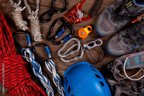 Climbing equipment for mountaineering and hiking helmet, hammer, carabiner, trekking shoes and other on wooden background, top view