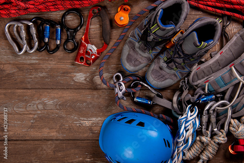 Climbing equipment for mountaineering and hiking helmet, hammer, carabiner, trekking shoes and other on wooden background, top view