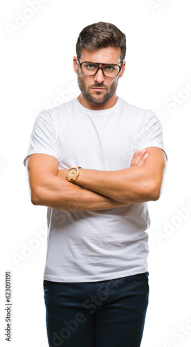 Young handsome man wearing glasses over isolated background skeptic and nervous, disapproving expression on face with crossed arms. Negative person.