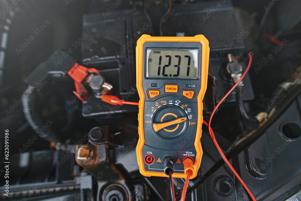 Multimeter checking car battery voltage level. Check car battery using voltmeter. Man check up