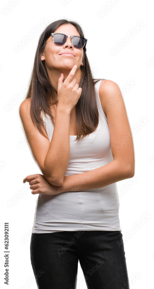 Young beautiful hispanic wearing sunglasses looking confident at the camera with smile with crossed arms and hand raised on chin. Thinking positive. Young beautiful hispanic wearing sunglasses looking confident at the camera with smile with crossed arms and hand raised on chin. Thinking positive.