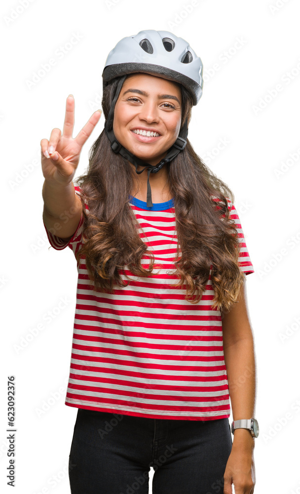 Young arab cyclist woman wearing safety helmet over isolated background smiling with happy face winking at the camera doing victory sign. Number two. Young arab cyclist woman wearing safety helmet over isolated background smiling with happy face winking at the camera doing victory sign. Number two.