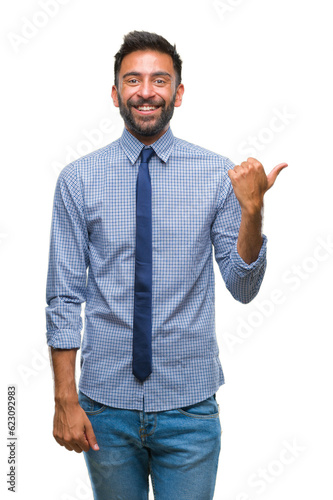 Adult hispanic business man over isolated background smiling with happy face looking and pointing to the side with thumb up. © Krakenimages.com