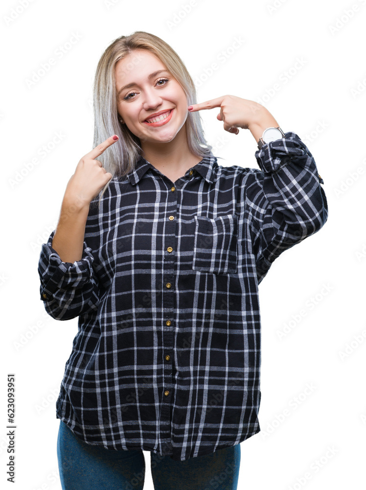 Young blonde woman over isolated background smiling confident showing and pointing with fingers teeth and mouth. Health concept. Young blonde woman over isolated background smiling confident showing and pointing with fingers teeth and mouth. Health concept.