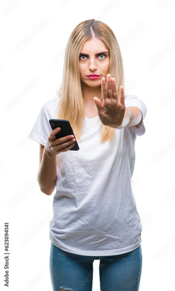 Young beautiful blonde woman using smartphone over isolated background with open hand doing stop sign with serious and confident expression, defense gesture Young beautiful blonde woman using smartphone over isolated background with open hand doing stop sign with serious and confident expression, defense gesture