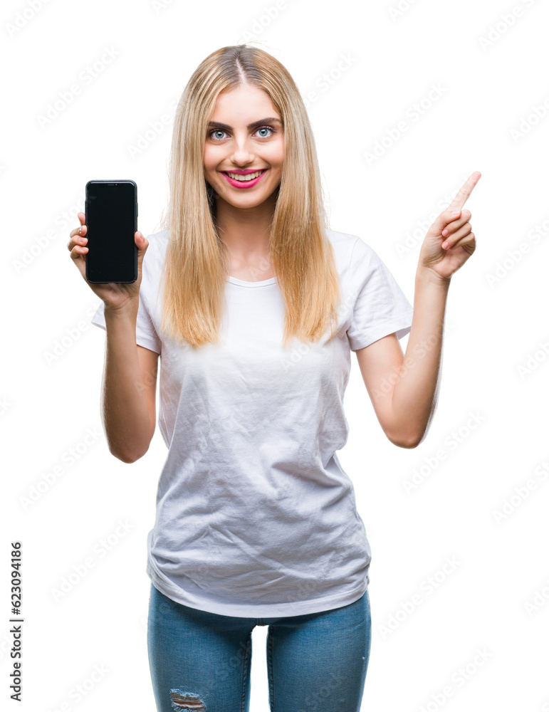 Young beautiful blonde woman showing smartphone over isolated background very happy pointing with hand and finger to the side Young beautiful blonde woman showing smartphone over isolated background very happy pointing with hand and finger to the side