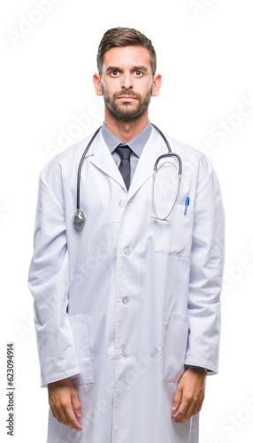 Young handsome doctor man over isolated background with serious expression on face. Simple and natural looking at the camera.