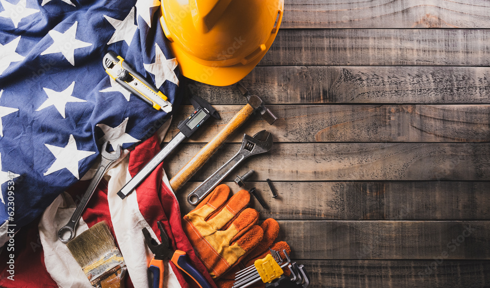 Happy Labor day concept. American flag with different construction tools on dark wooden background.