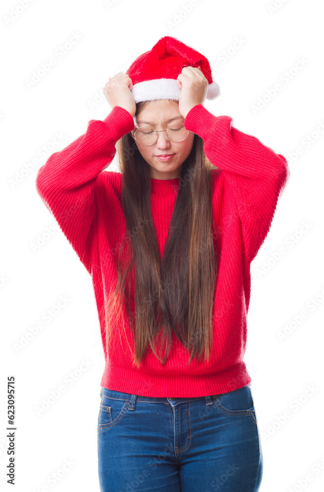 Young Chinese woman over isolated background wearing christmas hat suffering from headache desperate and stressed because pain and migraine. Hands on head.