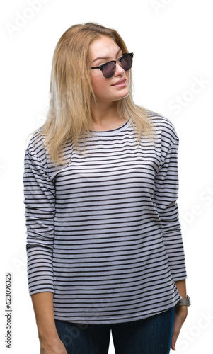 Young caucasian woman wearing sunglasses over isolated background looking away to side with smile on face, natural expression. Laughing confident.