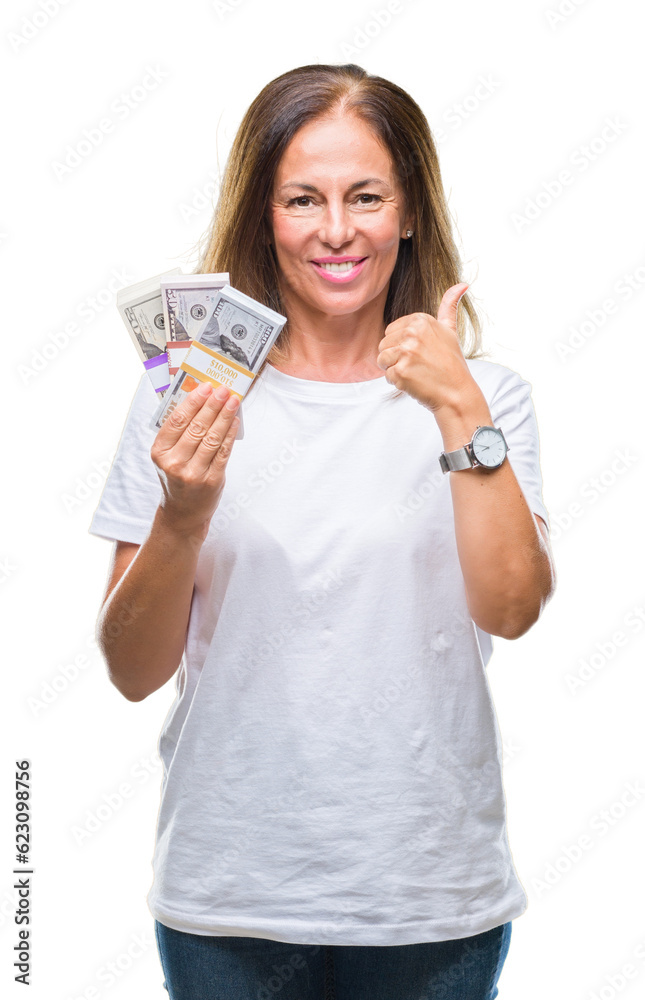 Middle age hispanic woman holding bunch of dollars over isolated background happy with big smile doing ok sign, thumb up with fingers, excellent sign Middle age hispanic woman holding bunch of dollars over isolated background happy with big smile doing ok sign, thumb up with fingers, excellent sign