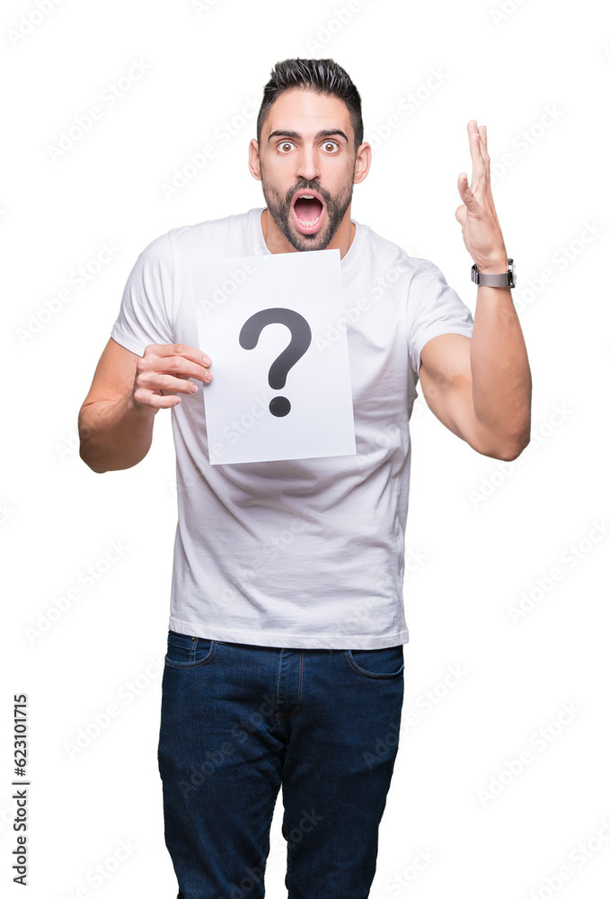 Handsome young man holding paper with question mark over isolated background very happy and excited, winner expression celebrating victory screaming with big smile and raised hands Handsome young man holding paper with question mark over isolated background very happy and excited, winner expression celebrating victory screaming with big smile and raised hands