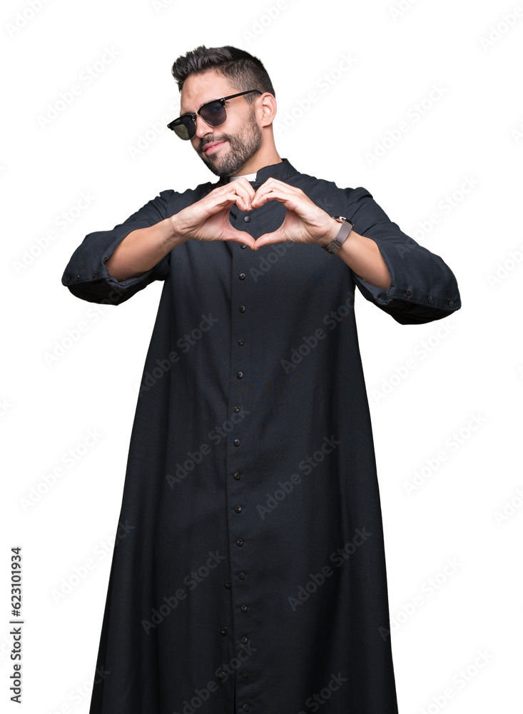 Young Christian priest wearing sunglasses over isolated background smiling in love showing heart symbol and shape with hands. Romantic concept.