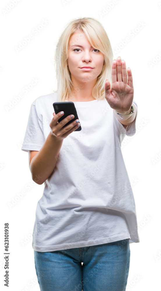 Young beautiful blonde woman using smartphone over isolated background with open hand doing stop sign with serious and confident expression, defense gesture Young beautiful blonde woman using smartphone over isolated background with open hand doing stop sign with serious and confident expression, defense gesture