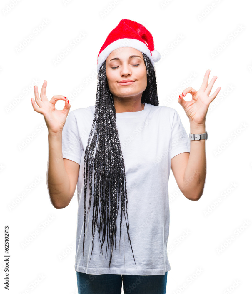 Young braided hair african american girl wearing christmas hat over isolated background relax and smiling with eyes closed doing meditation gesture with fingers. Yoga concept. Young braided hair african american girl wearing christmas hat over isolated background relax and smiling with eyes closed doing meditation gesture with fingers. Yoga concept.