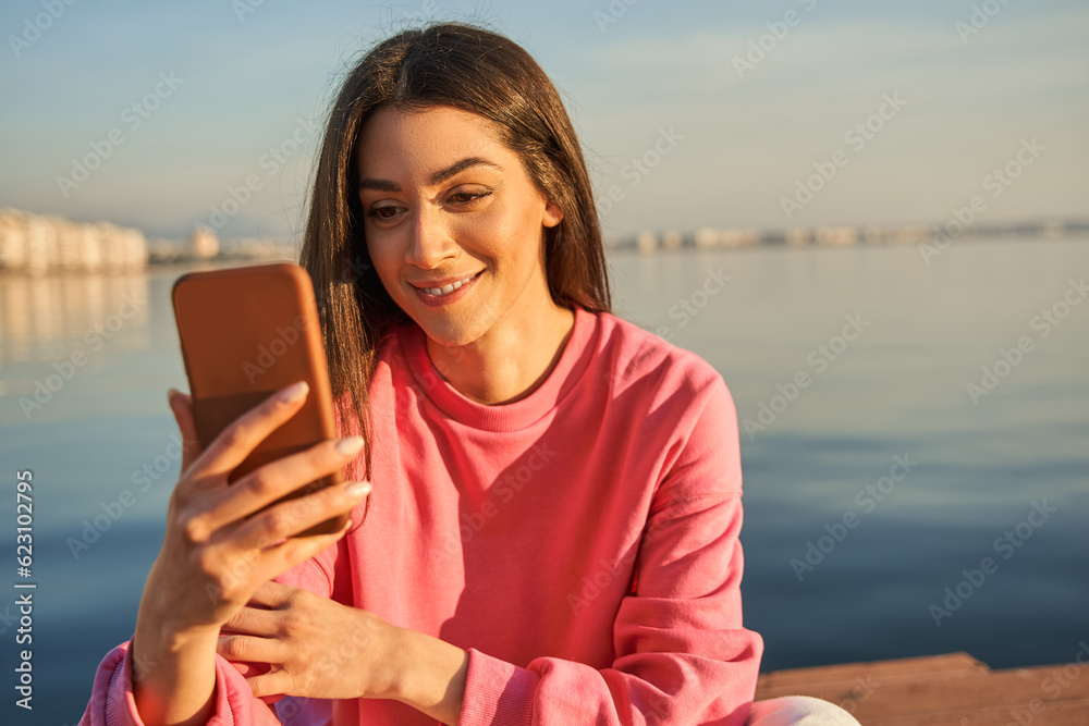 Lovely brunette girl making selfie at the summer sea landscape with water at the background