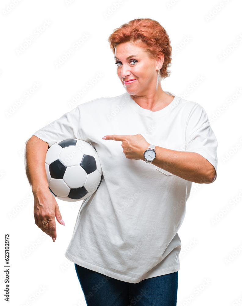 Atrractive senior caucasian redhead woman holding soccer ball over isolated background very happy pointing with hand and finger Atrractive senior caucasian redhead woman holding soccer ball over isolated background very happy pointing with hand and finger