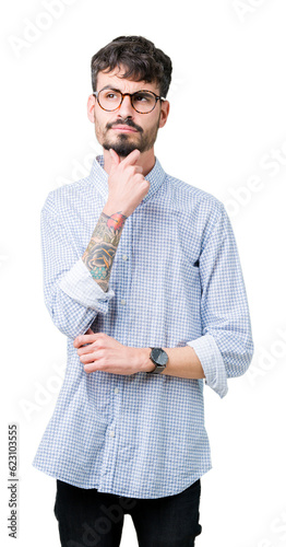 Young handsome man wearing glasses over isolated background with hand on chin thinking about question, pensive expression. Smiling with thoughtful face. Doubt concept.