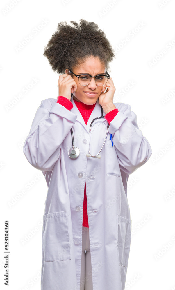 Young afro american doctor woman over isolated background covering ears with fingers with annoyed expression for the noise of loud music. Deaf concept. Young afro american doctor woman over isolated background covering ears with fingers with annoyed expression for the noise of loud music. Deaf concept.