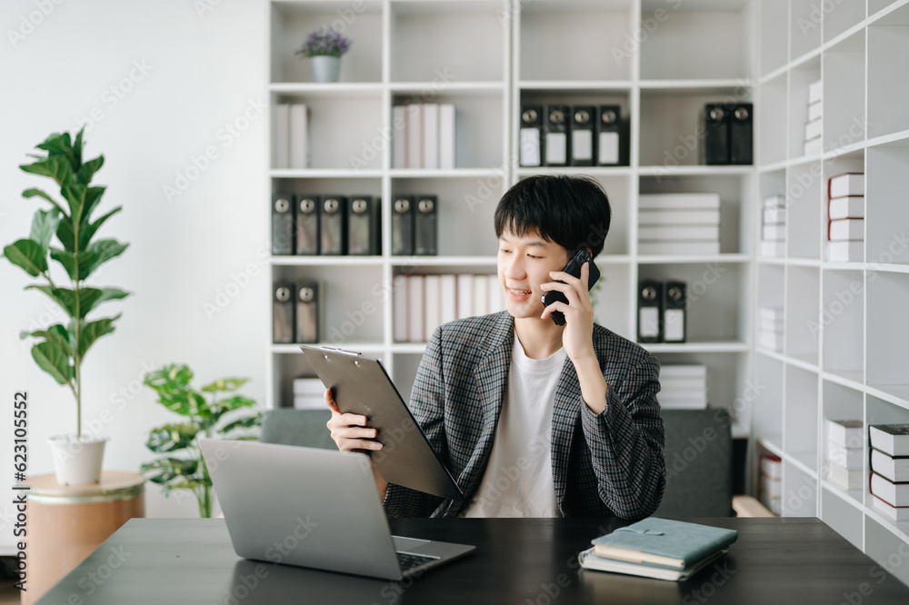 Young business man working at modern office with laptop, tablet and taking notes on the paper.. Young business man working at modern office with laptop, tablet and taking notes on the paper..