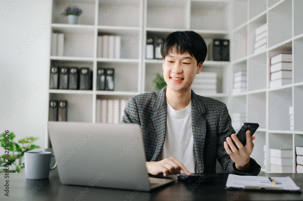 Young business man working at modern office with laptop, tablet and taking notes on the paper.. Young business man working at modern office with laptop, tablet and taking notes on the paper..