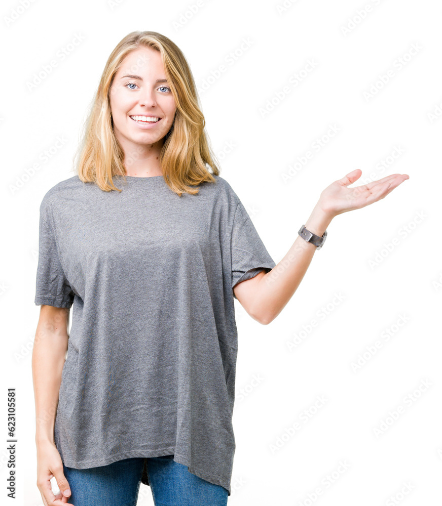 Fototapeta premium Beautiful young woman wearing oversize casual t-shirt over isolated background smiling cheerful presenting and pointing with palm of hand looking at the camera.