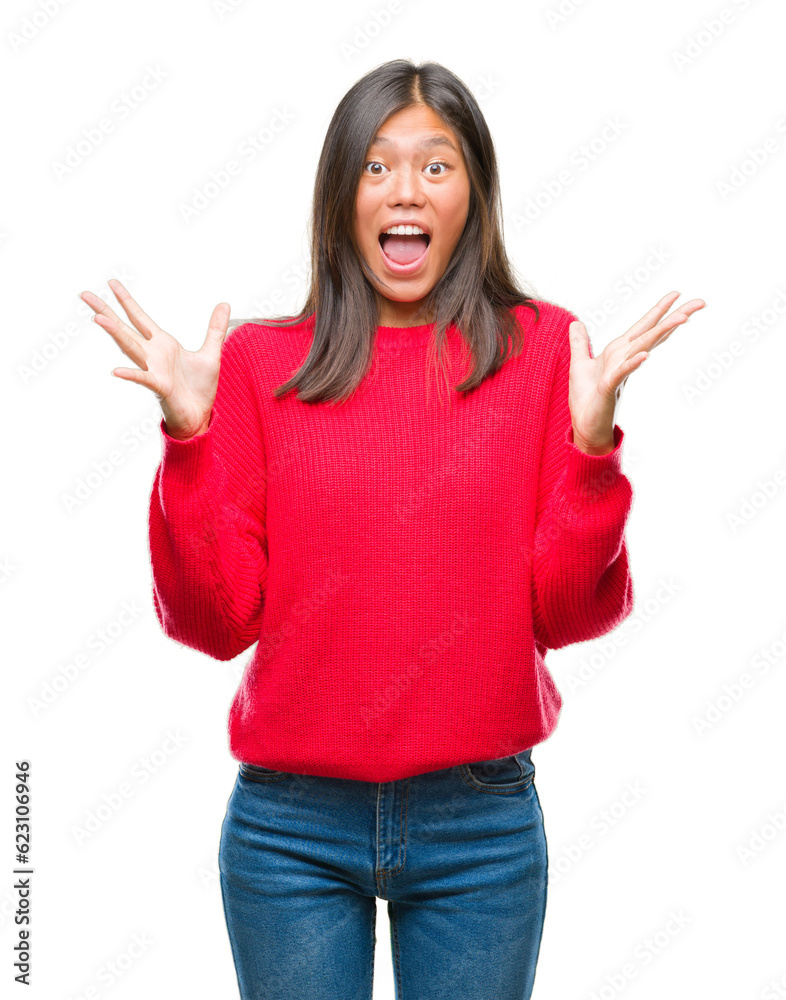 Young asian woman wearing winter sweater over isolated background celebrating crazy and amazed for success with arms raised and open eyes screaming excited. Winner concept Young asian woman wearing winter sweater over isolated background celebrating crazy and amazed for success with arms raised and open eyes screaming excited. Winner concept