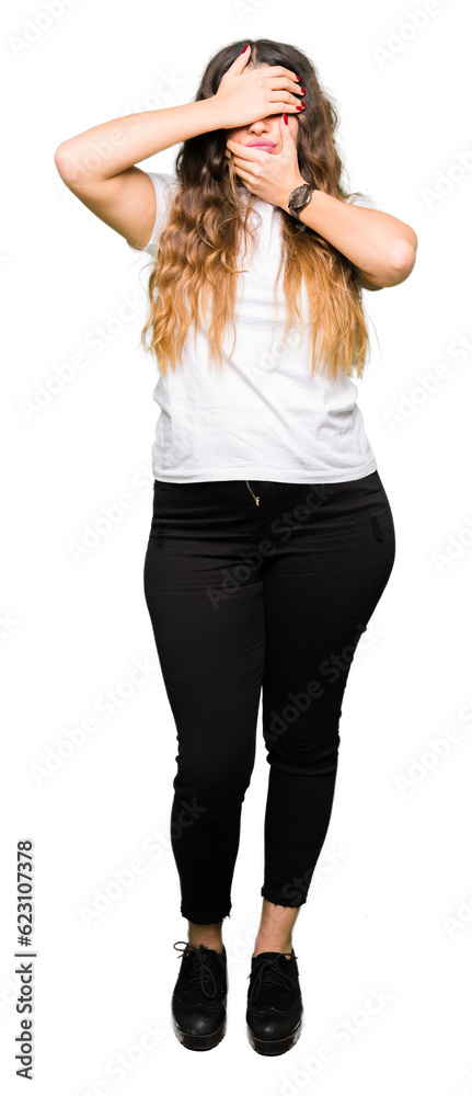 Young beautiful woman wearing casual white t-shirt Covering eyes and mouth with hands, surprised and shocked. Hiding emotion Young beautiful woman wearing casual white t-shirt Covering eyes and mouth with hands, surprised and shocked. Hiding emotion