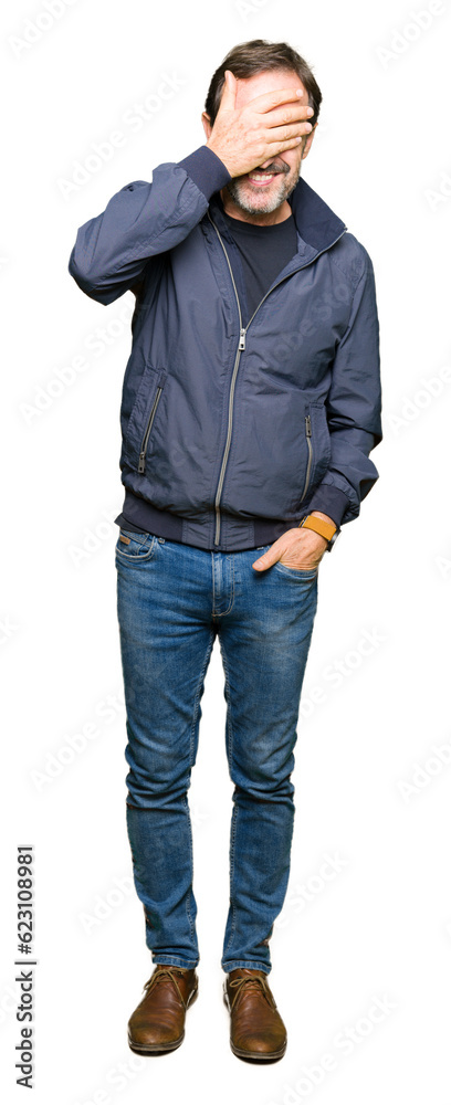 Middle age handsome man wearing a jacket smiling and laughing with hand on face covering eyes for surprise. Blind concept. Middle age handsome man wearing a jacket smiling and laughing with hand on face covering eyes for surprise. Blind concept.
