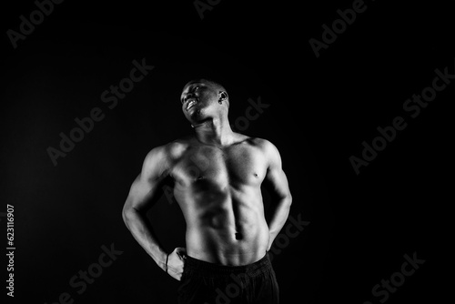 Portrait of an athletic african american man topless smiling, yellow, red and black background © Ivan Zelenin