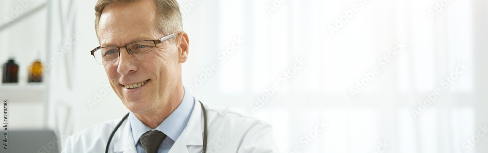 Cheerful healthcare worker using laptop in clinic Cheerful healthcare worker using laptop in clinic