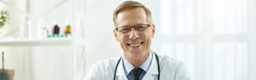 Joyful doctor sitting at the table with documents at work Joyful doctor sitting at the table with documents at work