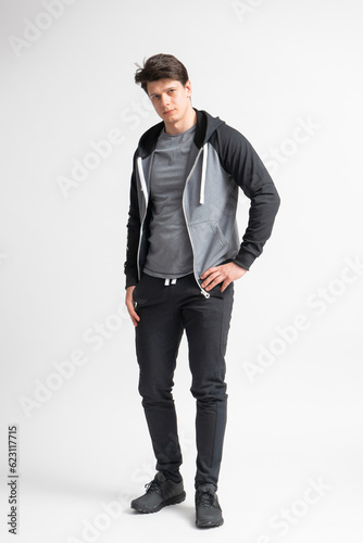 Young dark-haired man in a black tracksuit, gray t-shirt and running shoes © dimetradim