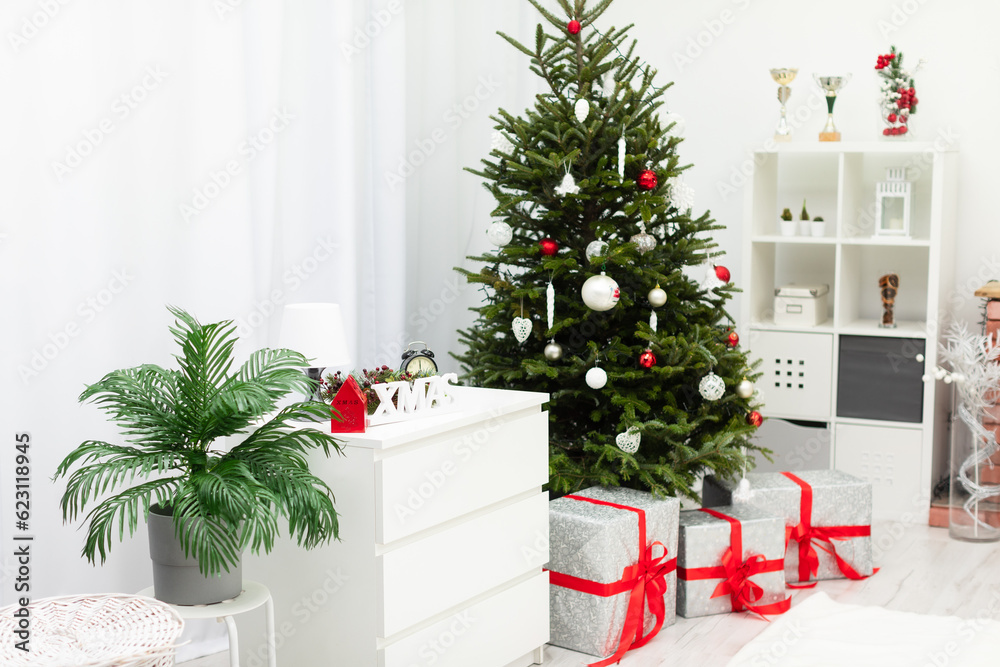 Large gifts lying under a decorated Christmas tree in a bright room