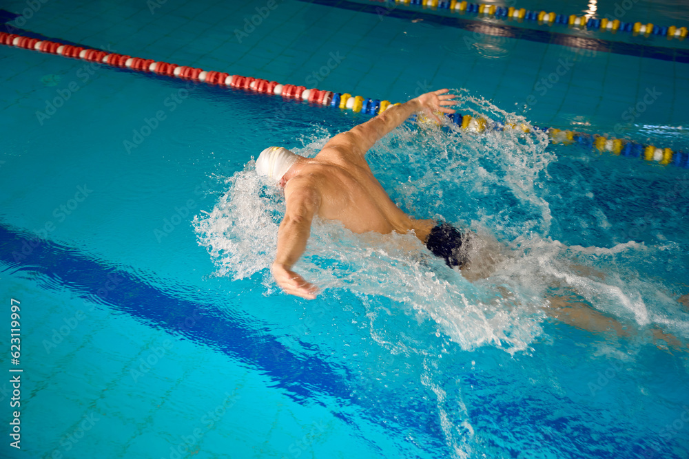 Adult man in white cap is swimming