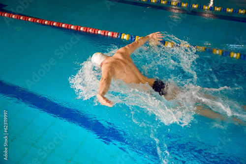 Adult man in white cap is swimming