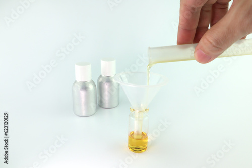 chemical beaker , flask is on white table with blotting paper , fragrance bottle and essential oil bottle are used to blend the nice scent for making perfume and candle by perfumer in the laboratory