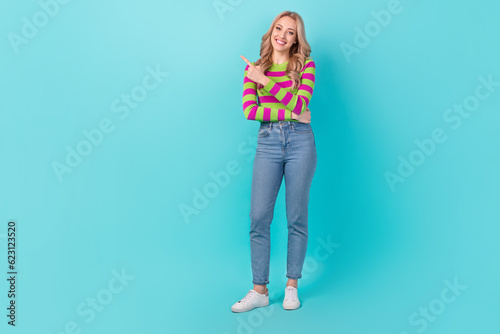 Full length photo of friendly sweet woman dressed striped sweater pointing finger empty space isolated turquoise color background