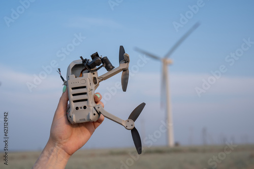 Slika na platnu Woman holding a crashed drone against the backdrop of windmills.