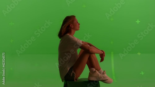 Silhouette young caucasian woman sitting on the top of a mountain or roof watching the sunset with beautiful landscape on Green screen background, chroma key.