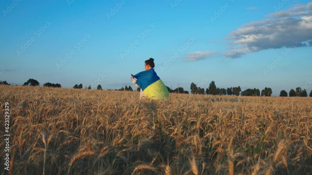 Fantastic view of a young Ukrainian woman with the national flag in a wheat field. Sunlight around. Harvesting. Ukraine, independence, freedom. Patriot symbol, victory in war. Slow motion Fantastic view of a young Ukrainian woman with the national flag in a wheat field. Sunlight around. Harvesting. Ukraine, independence, freedom. Patriot symbol, victory in war. Slow motion