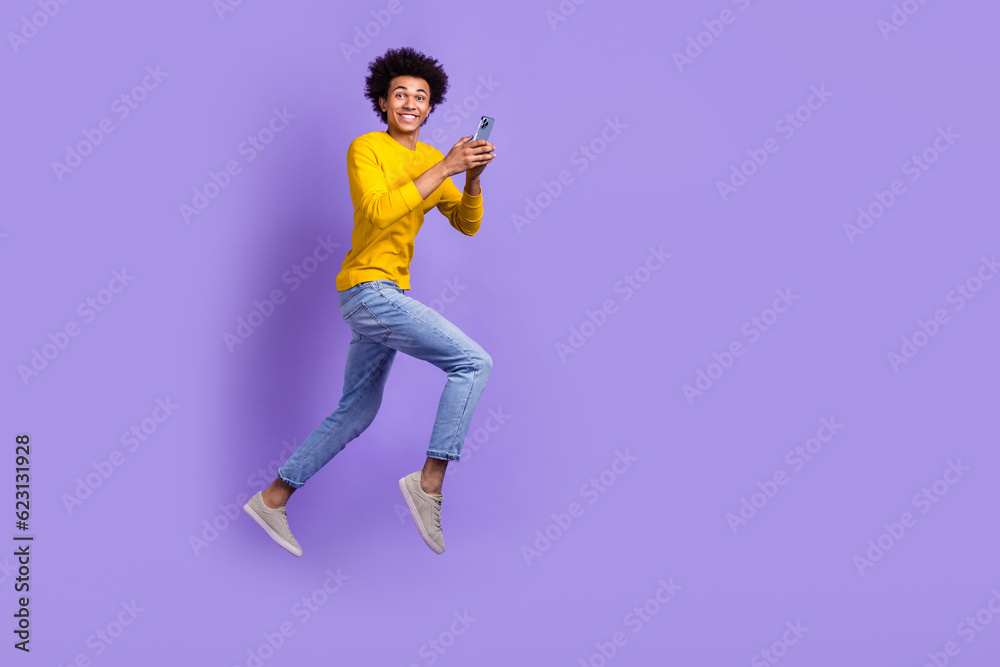 Full body size photo of funky positive young guy running fast speed use gadget texting online sms isolated over violet color background