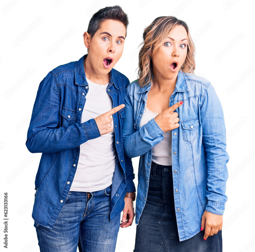 Couple of women wearing casual clothes surprised pointing with finger to the side, open mouth amazed expression. Couple of women wearing casual clothes surprised pointing with finger to the side, open mouth amazed expression.