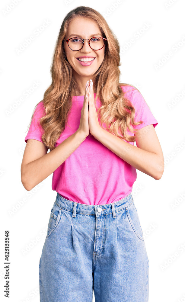 Young beautiful caucasian woman with blond hair wearing casual clothes and glasses praying with hands together asking for forgiveness smiling confident. Young beautiful caucasian woman with blond hair wearing casual clothes and glasses praying with hands together asking for forgiveness smiling confident.