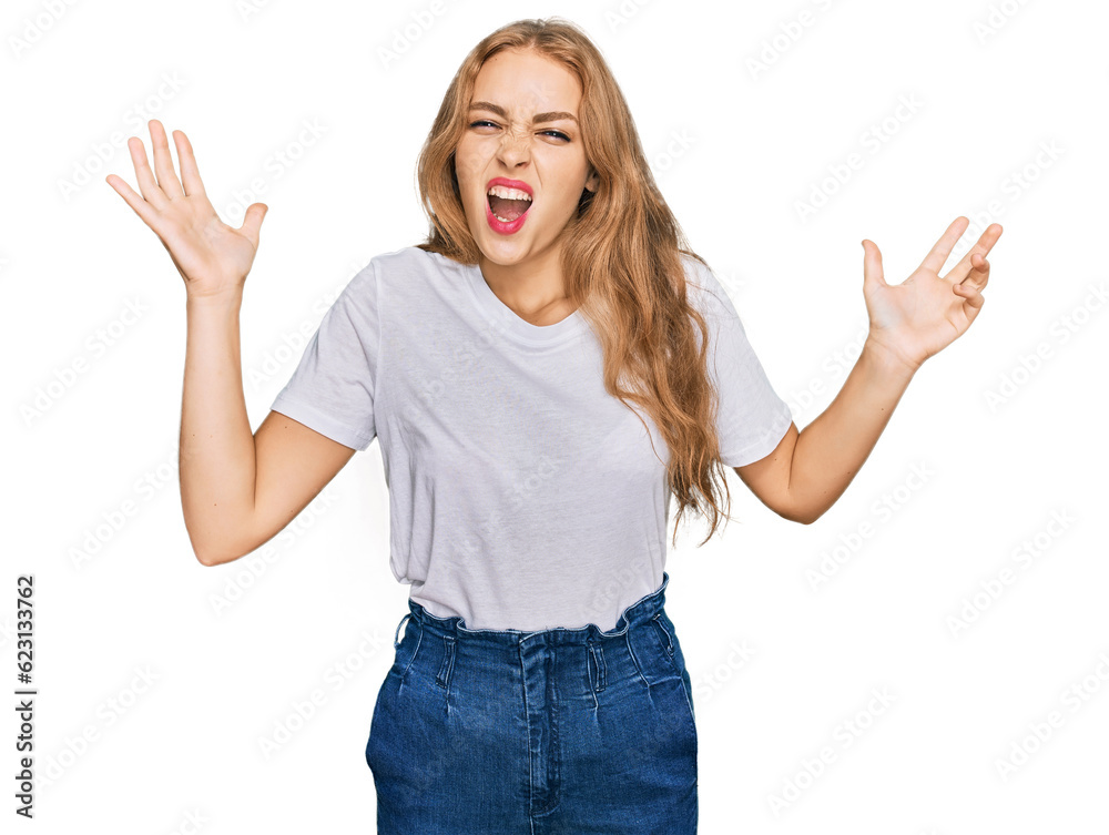 Young caucasian girl wearing casual white t shirt crazy and mad shouting and yelling with aggressive expression and arms raised. frustration concept. Young caucasian girl wearing casual white t shirt crazy and mad shouting and yelling with aggressive expression and arms raised. frustration concept.