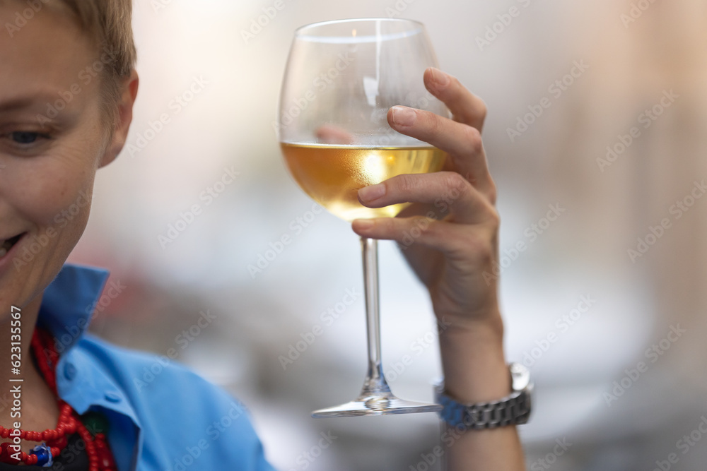 An adult stylish woman holding a glass on wine outdoors
