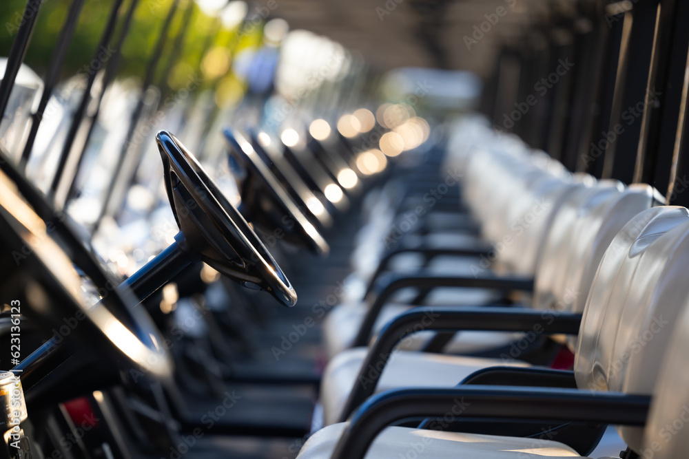 Focus steering wheel golf carts for golf player on golf course. golf course carts cars at luxury golf club sport venue in neat line row.