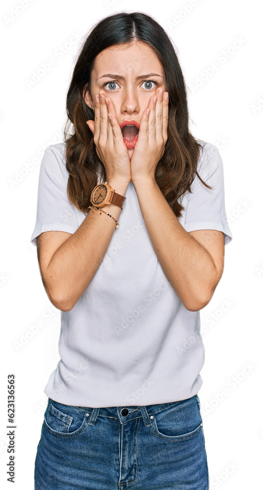 Young beautiful woman wearing casual white t shirt afraid and shocked, surprise and amazed expression with hands on face