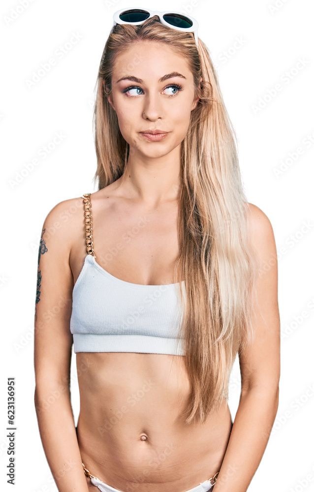 Fototapeta premium Beautiful young blonde woman wearing bikini smiling looking to the side and staring away thinking.