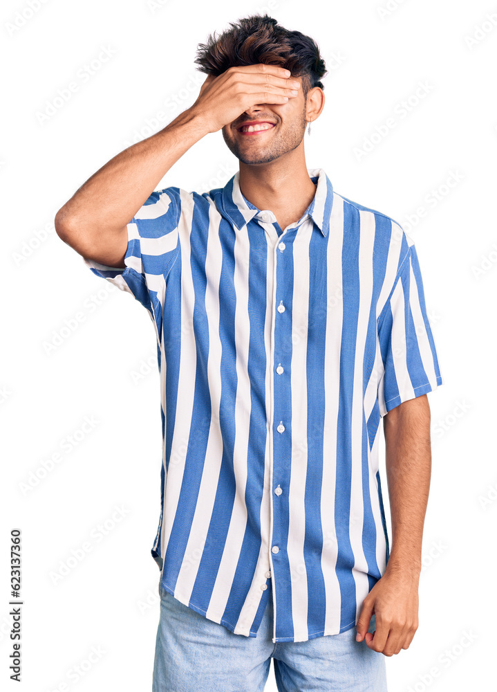 Young hispanic man wearing casual clothes smiling and laughing with hand on face covering eyes for surprise. blind concept. Young hispanic man wearing casual clothes smiling and laughing with hand on face covering eyes for surprise. blind concept.
